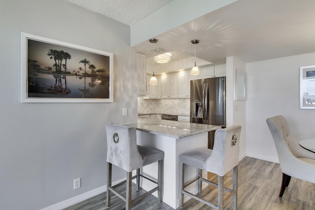 kitchen with light stone countertops, a breakfast bar area, decorative backsplash, appliances with stainless steel finishes, and a peninsula