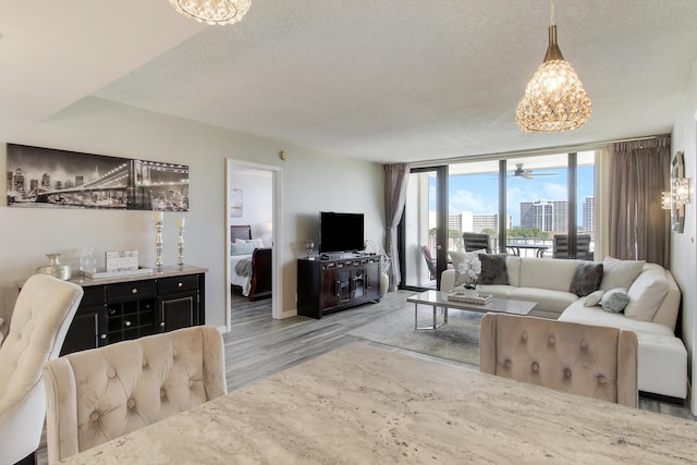 living room with a notable chandelier, wood finished floors, a textured ceiling, and expansive windows