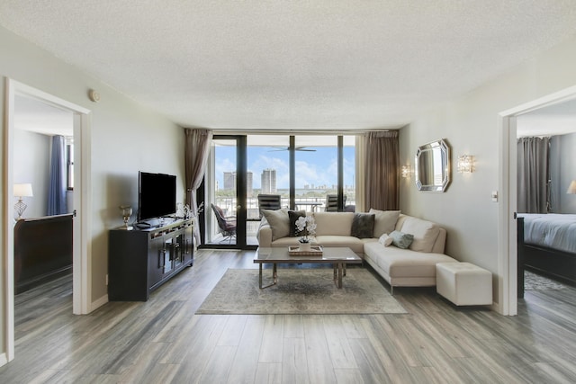 336 Golfview Rd Unit 807, North Palm Beach, FL 33408 - living area with wood finished floors, baseboards, a textured ceiling, expansive windows, and ceiling fan with notable chandelier