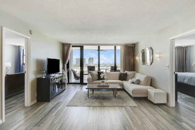 living area with a textured ceiling, wood finished floors, and floor to ceiling windows