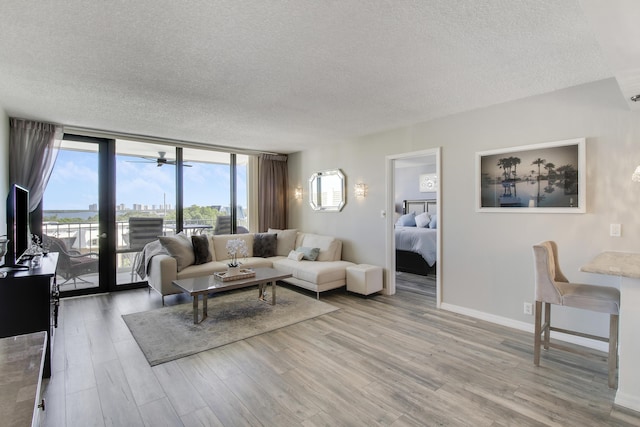 living room featuring a wall of windows, baseboards, a textured ceiling, and wood finished floors