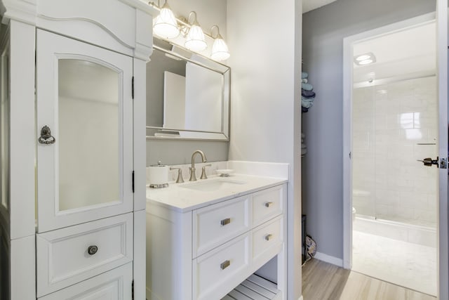 full bathroom featuring vanity, wood finished floors, a stall shower, and baseboards