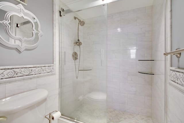 full bathroom with a wainscoted wall, toilet, tile walls, and a stall shower