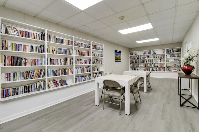 office space with built in features, a paneled ceiling, wood finished floors, and bookshelves