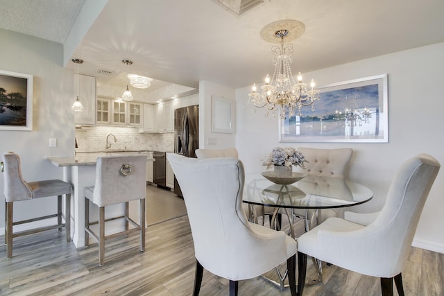 dining space featuring light wood-type flooring, visible vents, and baseboards