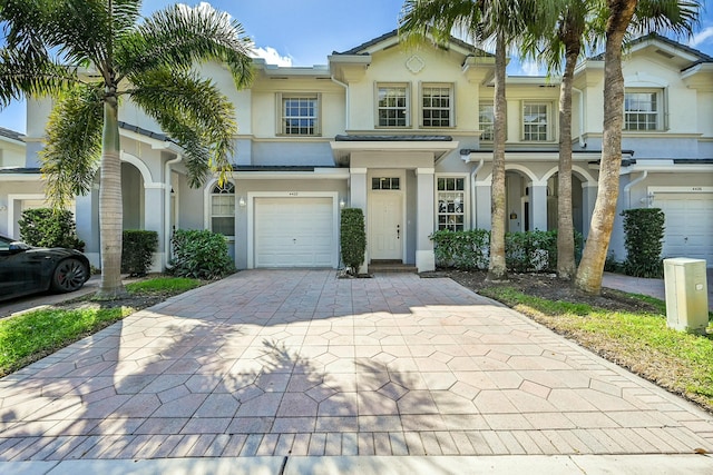 view of front of house featuring an attached garage, decorative driveway, and stucco siding