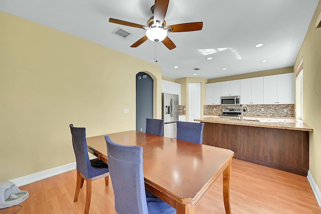 dining room featuring arched walkways, recessed lighting, visible vents, light wood-style flooring, and baseboards