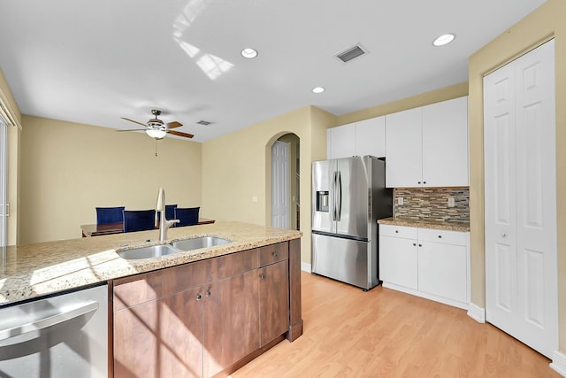 kitchen with arched walkways, light wood finished floors, visible vents, appliances with stainless steel finishes, and a sink