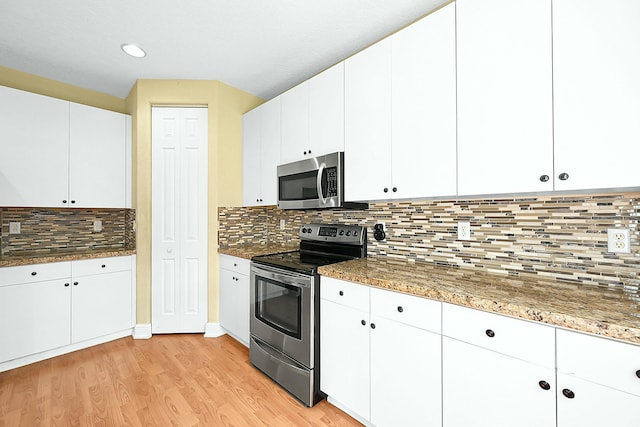 kitchen featuring light stone counters, stainless steel appliances, white cabinetry, light wood-type flooring, and backsplash