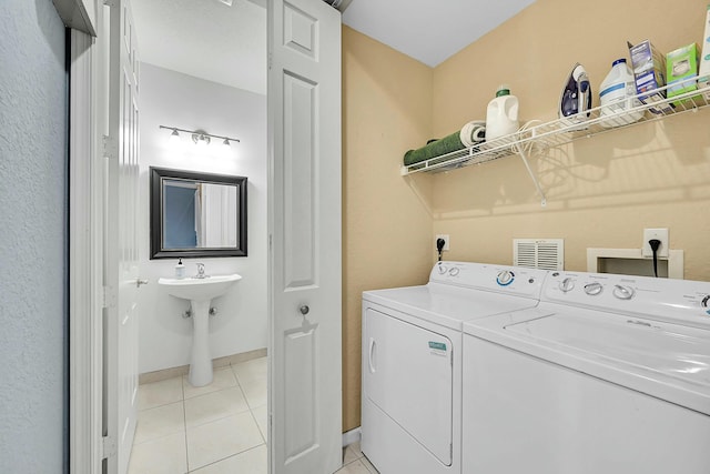 clothes washing area with laundry area, light tile patterned floors, baseboards, and separate washer and dryer