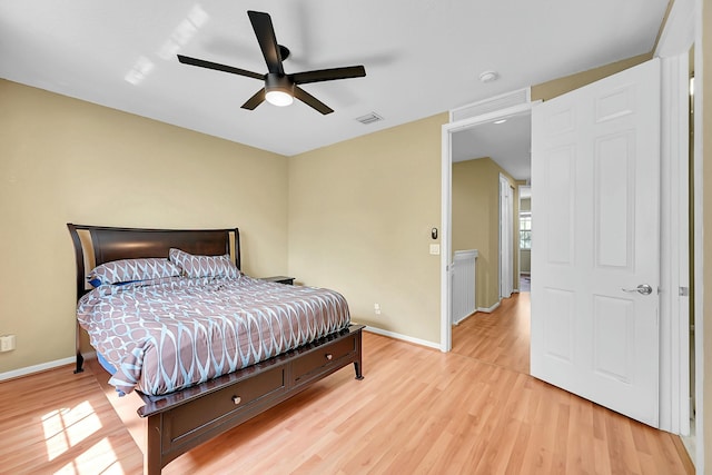 bedroom with light wood finished floors, visible vents, and baseboards