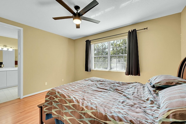 bedroom with light wood-style flooring, baseboards, a ceiling fan, and ensuite bathroom