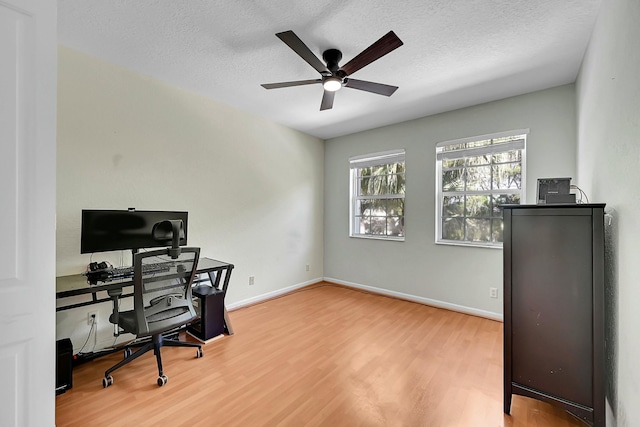 home office featuring ceiling fan, a textured ceiling, baseboards, and wood finished floors