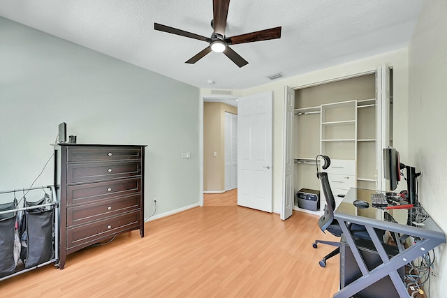 home office featuring ceiling fan, a textured ceiling, visible vents, baseboards, and light wood-type flooring