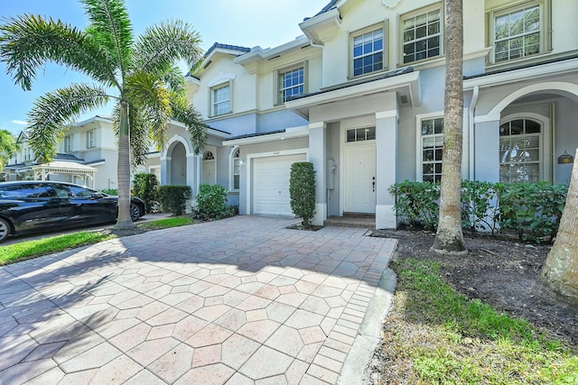 view of front facade featuring decorative driveway, an attached garage, and stucco siding