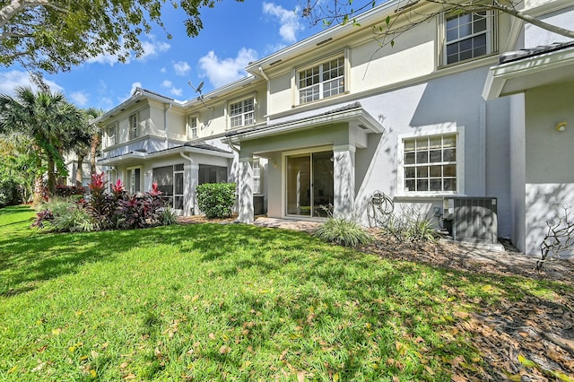 back of property featuring a yard, central AC unit, and stucco siding