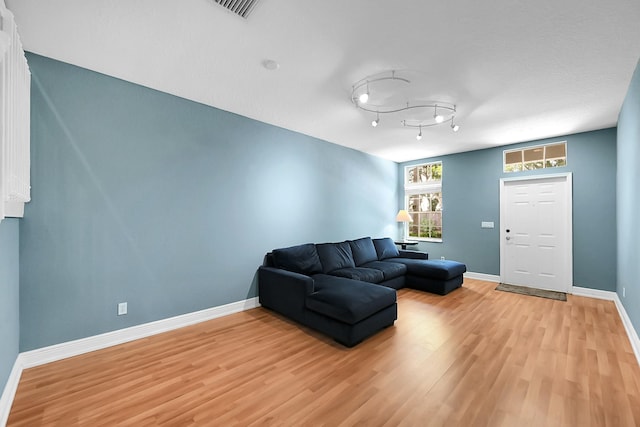 living room featuring light wood-type flooring, visible vents, and baseboards