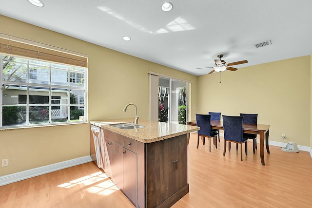 kitchen with baseboards, a sink, light stone countertops, and light wood-style floors