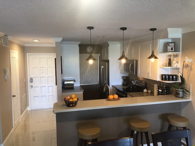 kitchen featuring appliances with stainless steel finishes, a breakfast bar area, ornamental molding, a peninsula, and backsplash