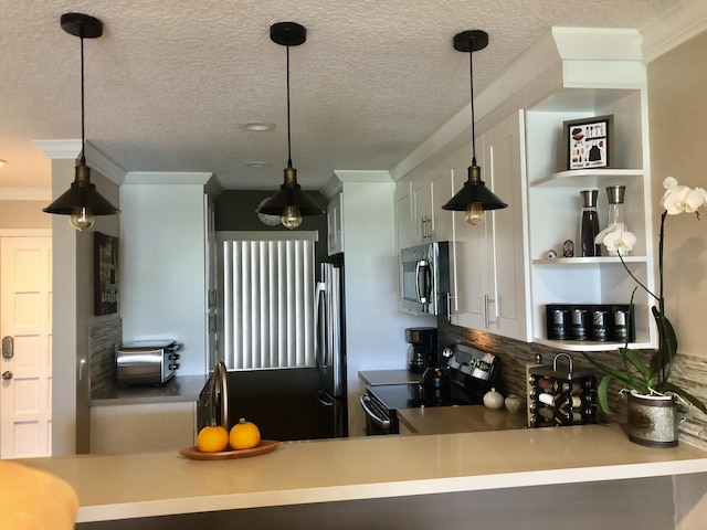 kitchen with a textured ceiling, stainless steel appliances, hanging light fixtures, and ornamental molding