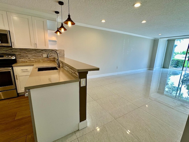 4822 Esedra Ct Unit 101, Lake Worth, FL 33467 - kitchen featuring appliances with stainless steel finishes, a sink, crown molding, white cabinetry, and a peninsula