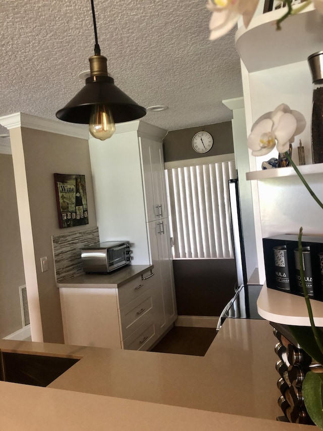 kitchen with crown molding, pendant lighting, and a textured ceiling