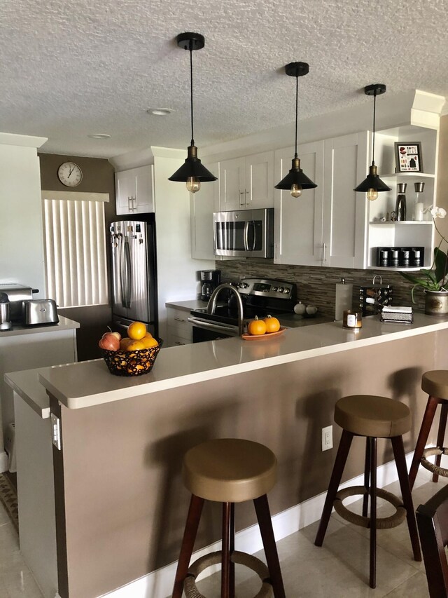 kitchen featuring stainless steel appliances, white cabinets, a sink, and tasteful backsplash