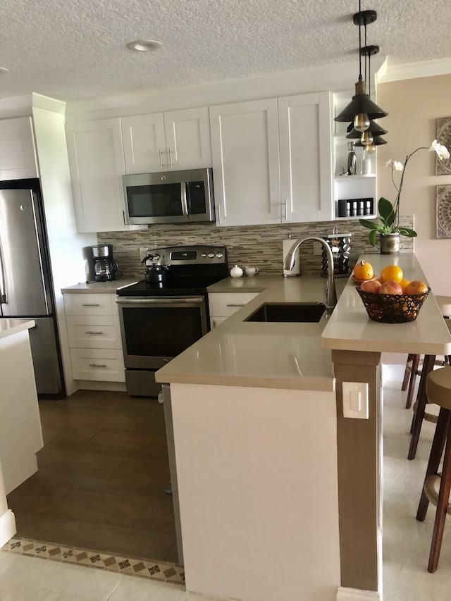 kitchen featuring tasteful backsplash, white cabinetry, stainless steel appliances, and a sink