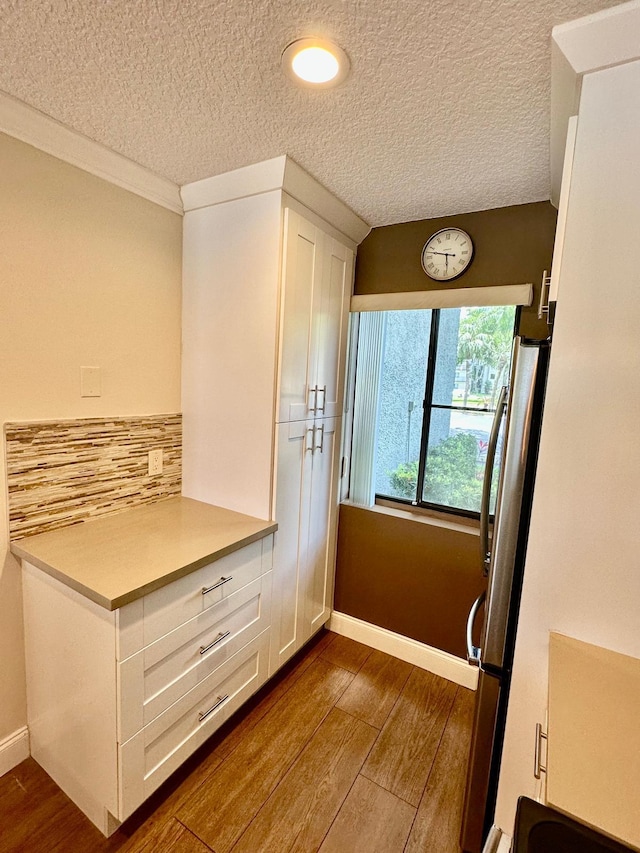 4822 Esedra Ct Unit 101, Lake Worth, FL 33467 - kitchen featuring dark wood-style flooring, a textured ceiling, white cabinetry, tasteful backsplash, and light countertops