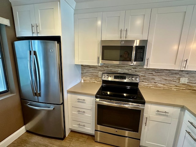 4822 Esedra Ct Unit 101, Lake Worth, FL 33467 - kitchen with stainless steel appliances, decorative backsplash, light countertops, white cabinets, and light wood-style flooring