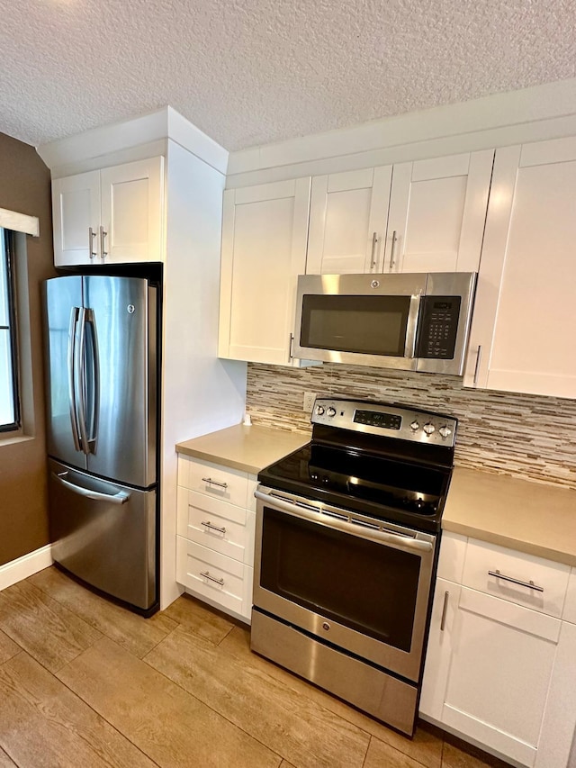 4822 Esedra Ct Unit 101, Lake Worth, FL 33467 - kitchen with stainless steel appliances, white cabinetry, backsplash, light countertops, and light wood-type flooring