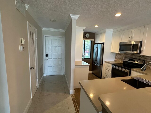 4822 Esedra Ct Unit 101, Lake Worth, FL 33467 - kitchen featuring stainless steel appliances, tasteful backsplash, white cabinets, baseboards, and a textured ceiling