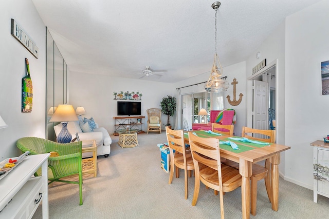 dining area featuring a ceiling fan, light colored carpet, and baseboards