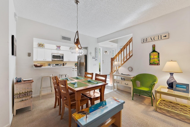 dining space featuring light carpet, stairway, visible vents, and a textured ceiling