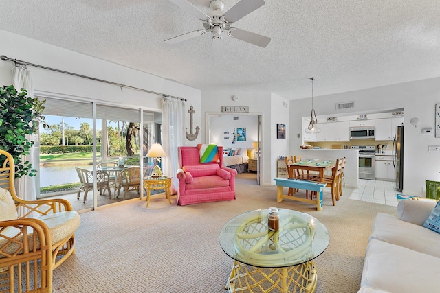 living room featuring a ceiling fan, light colored carpet, visible vents, and a textured ceiling