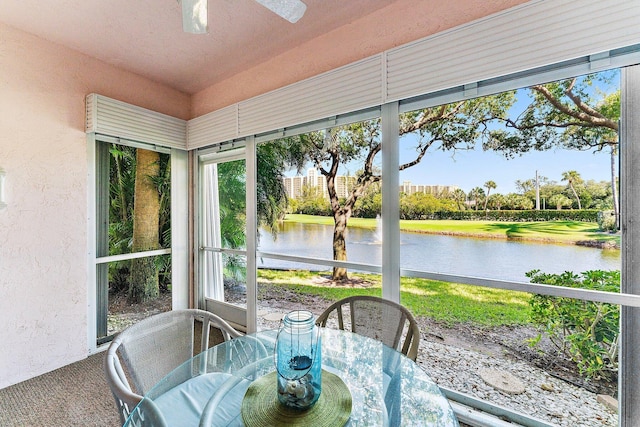 sunroom / solarium featuring a water view and a ceiling fan