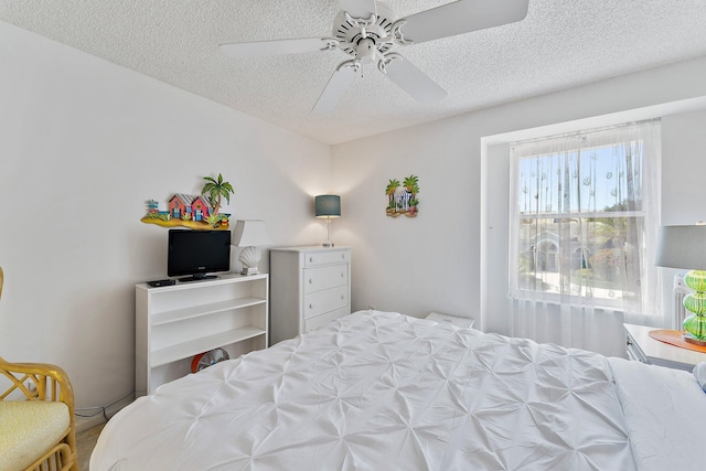 bedroom with ceiling fan and a textured ceiling