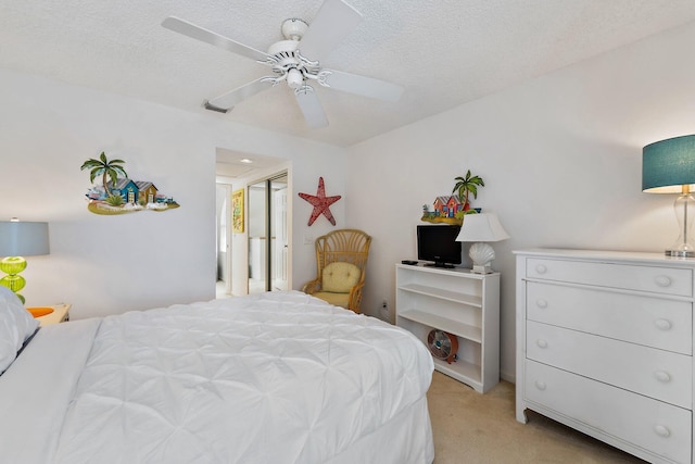 bedroom featuring light carpet, ceiling fan, and a textured ceiling