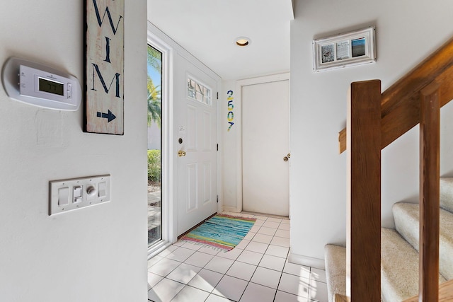 foyer entrance featuring light tile patterned floors and stairs