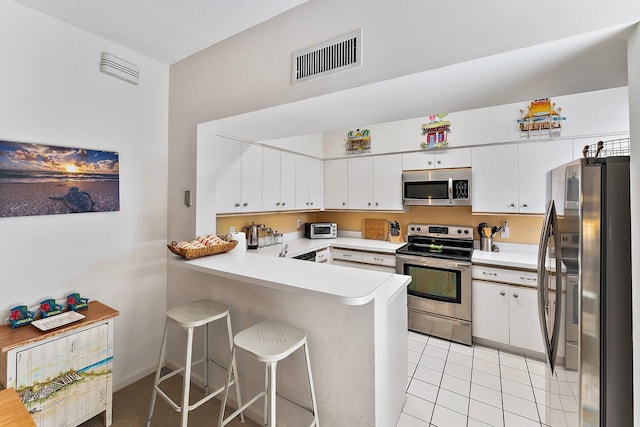 kitchen with light countertops, visible vents, appliances with stainless steel finishes, white cabinetry, and a peninsula