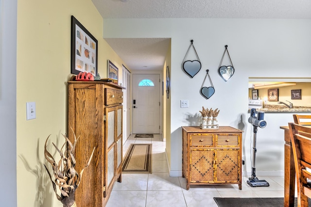 entrance foyer featuring a textured ceiling, light tile patterned floors, and baseboards