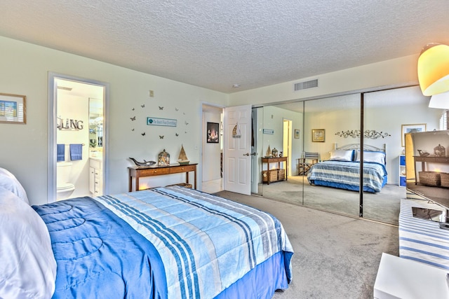 bedroom with carpet floors, a closet, visible vents, ensuite bathroom, and a textured ceiling