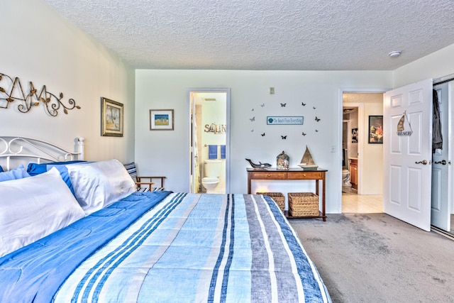 carpeted bedroom featuring a textured ceiling and ensuite bath