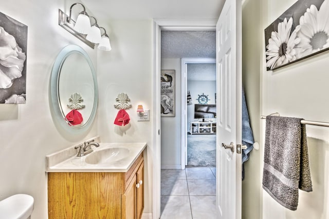 bathroom with a textured ceiling, toilet, vanity, and tile patterned floors