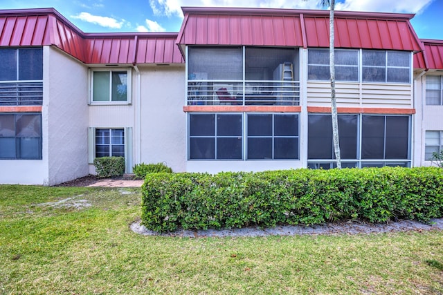 exterior space with a standing seam roof, a lawn, and metal roof