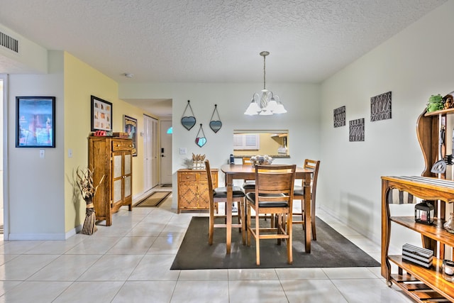 dining space featuring light tile patterned floors, baseboards, a chandelier, and a textured ceiling