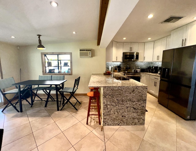 kitchen with visible vents, white cabinets, appliances with stainless steel finishes, a peninsula, and a sink