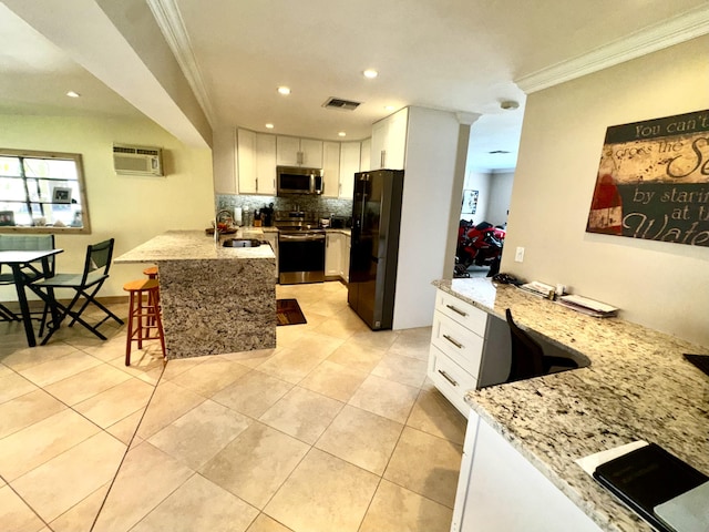 kitchen featuring stainless steel appliances, a peninsula, a sink, visible vents, and crown molding