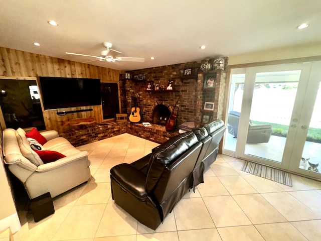 tiled living area featuring a brick fireplace, ceiling fan, wooden walls, and brick wall