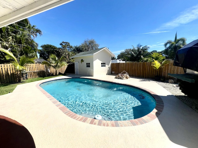 view of swimming pool featuring a fenced in pool, a fenced backyard, a patio, and an outdoor structure